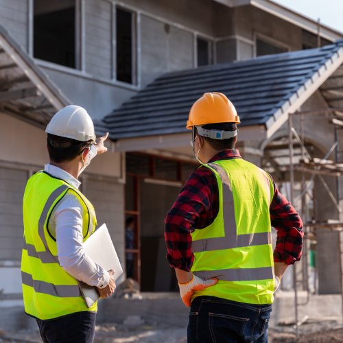 Two men are discussing something while looking at a house. There is scaffolding around the entry to the home.