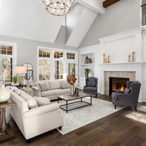 A cozy, open concept living room with vaulted ceilings and a fireplace. There are two light beige sofas in the center.